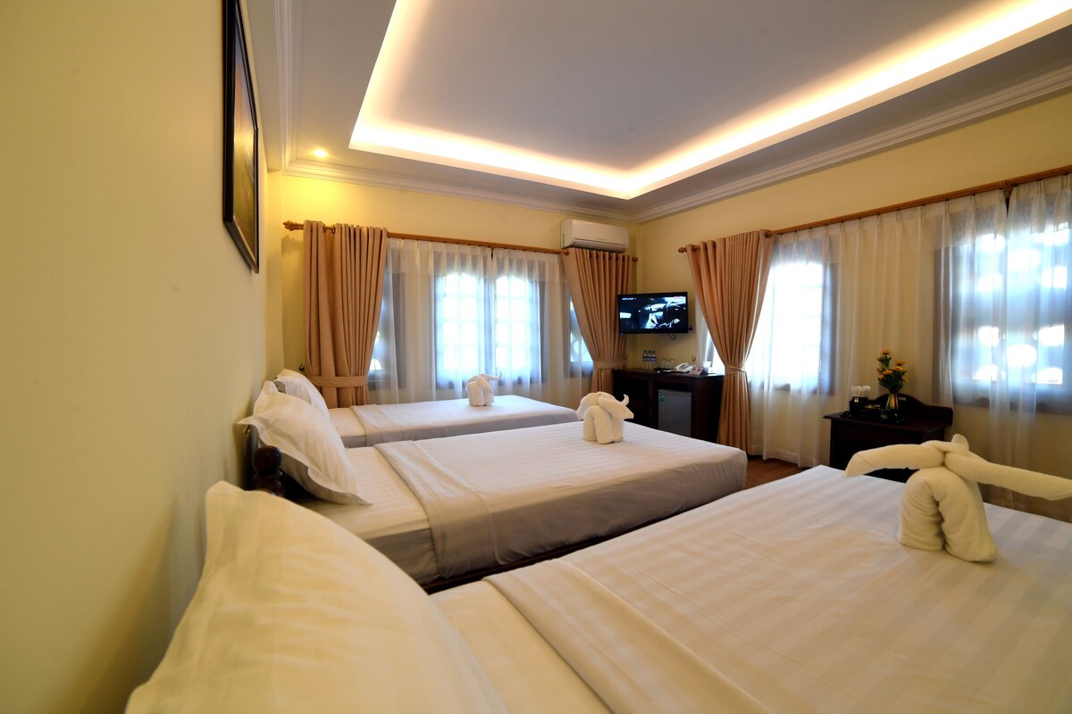 A hotel room with two beds, a television, and a desk with a computer.