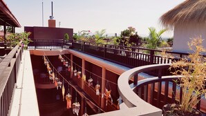 A multi-level outdoor area with a curved balcony, potted plants, and hanging decorations. - Bagan View Hotel (Nyaung-U)