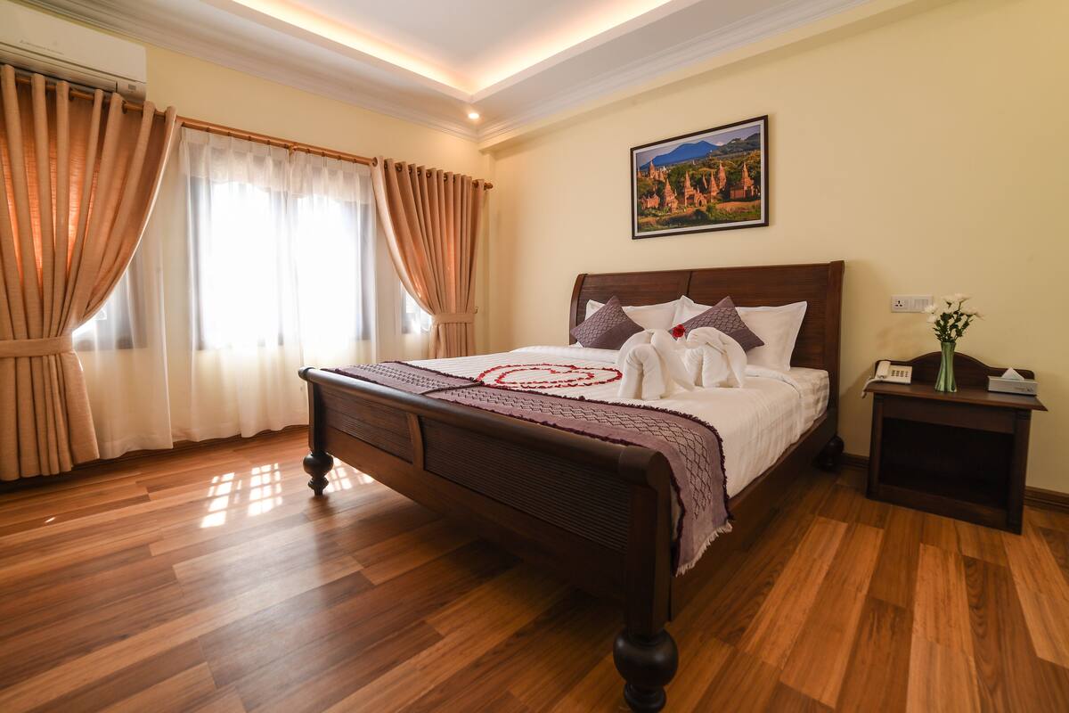Un dormitorio ordenado con una cama de madera, una mesita de noche y un cuadro en la pared.