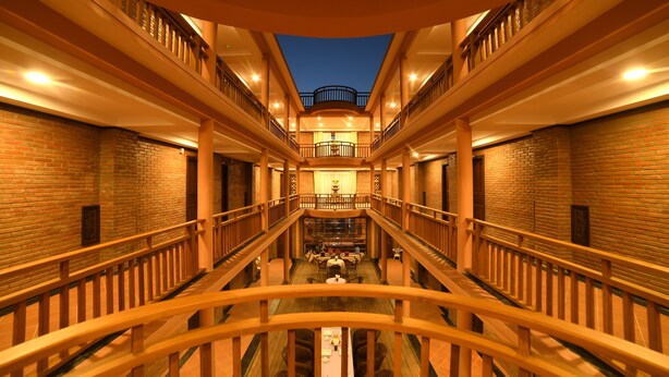 A multi-level atrium with a central open area, wooden railings, and brick walls. - Bagan View Hotel (Nyaung-U)