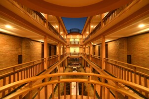 Un atrium à plusieurs niveaux, doté d’un espace central ouvert, de rampes en bois et de murs en briques.