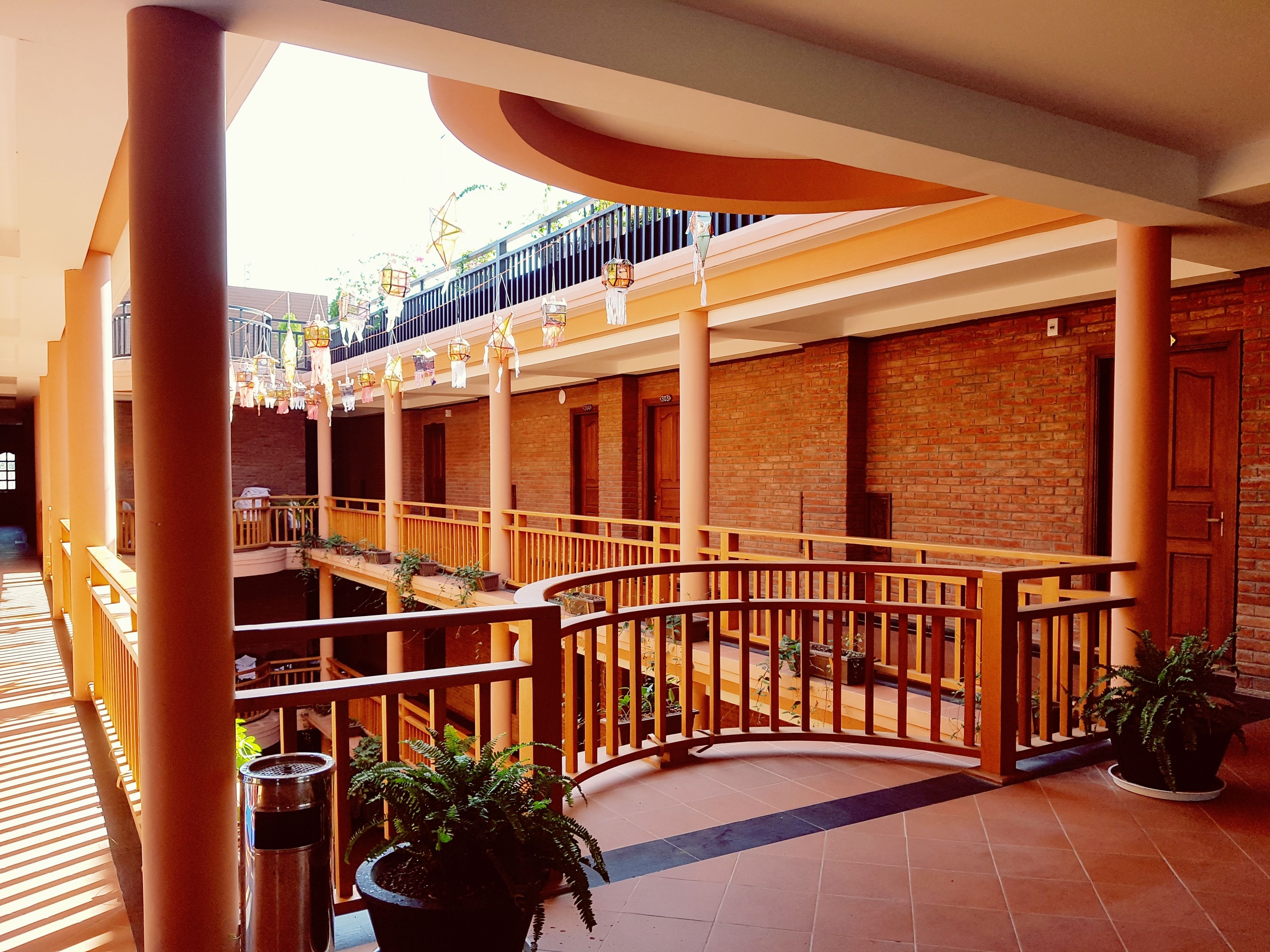 A multi-level atrium with brick walls, wooden railings, and potted plants.
