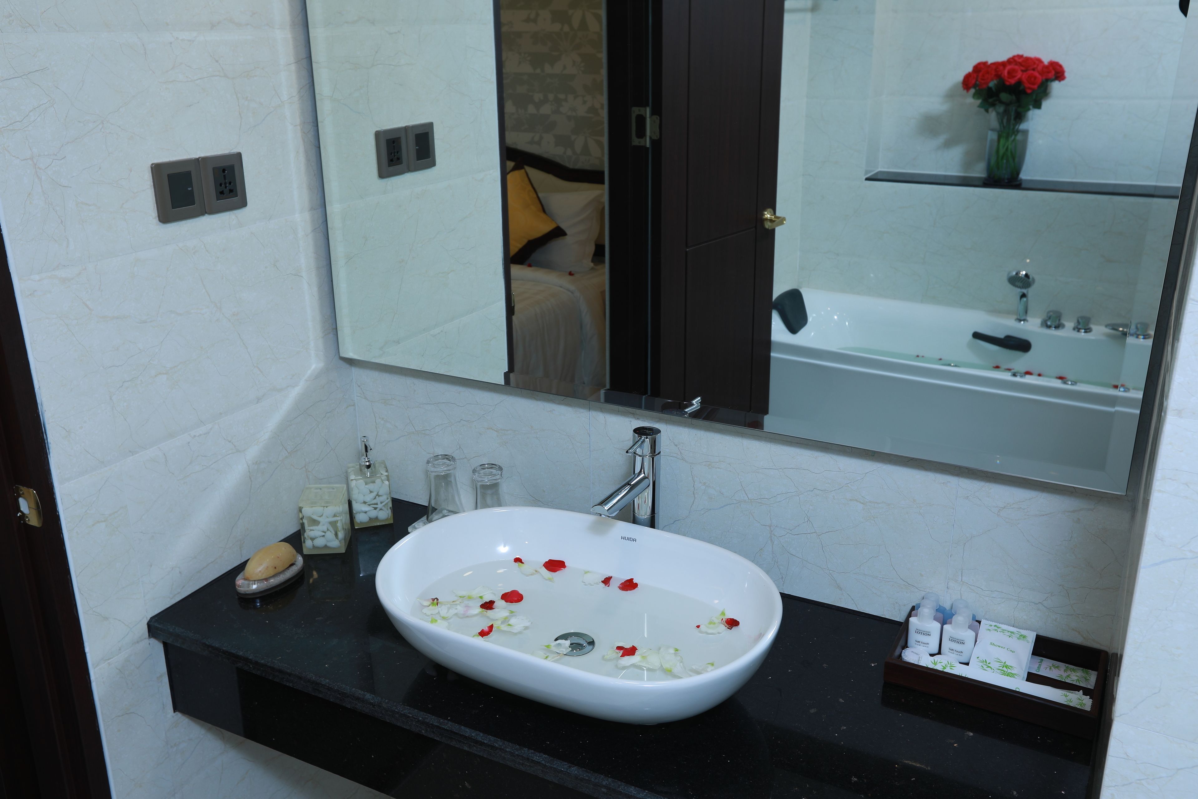 A bathroom with a white sink, a mirror, and a black countertop.