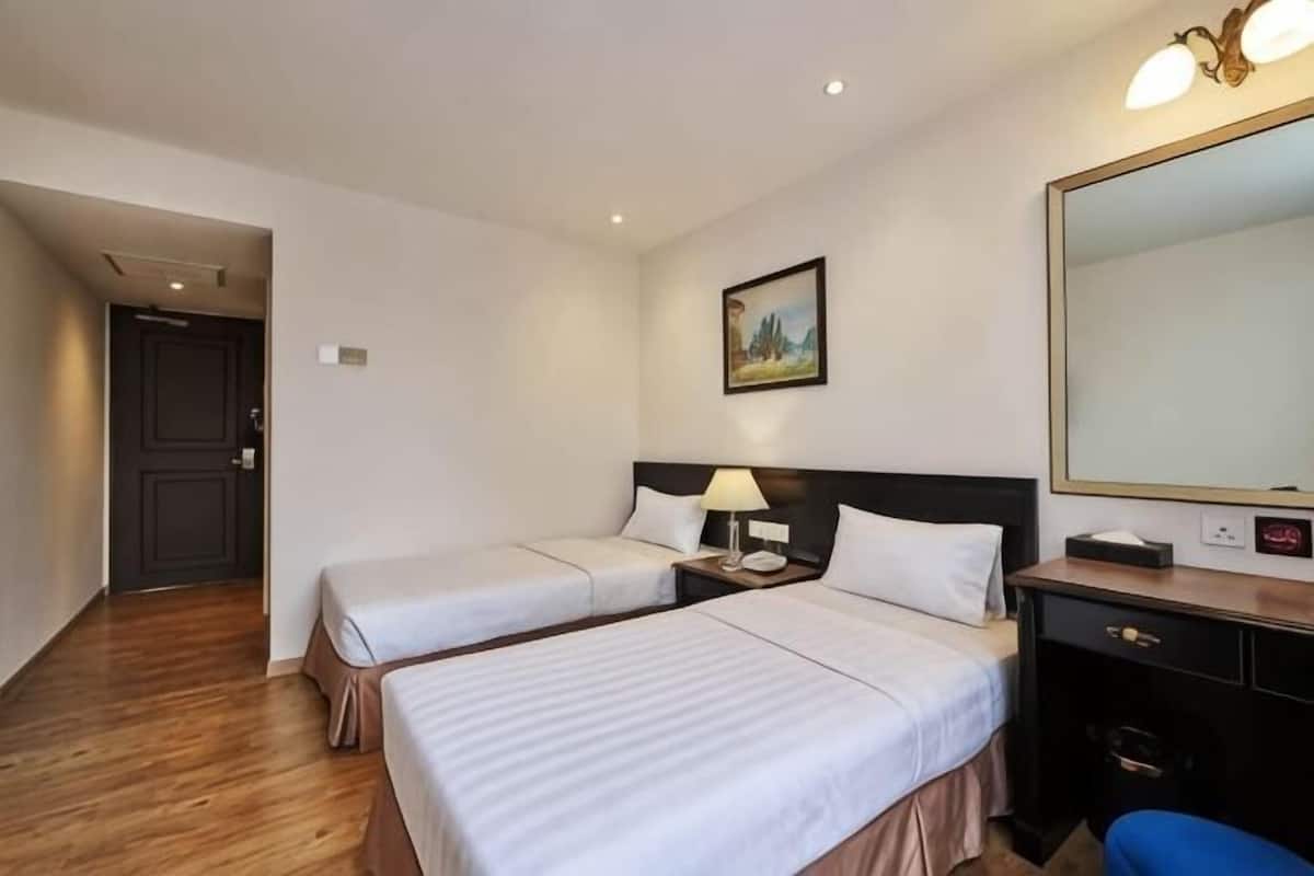 Une chambre d’hôtel avec deux lits, un bureau, une chaise, un miroir et une porte.