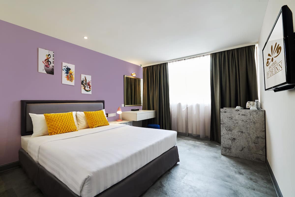 Une chambre d’hôtel avec un lit, un bureau, un miroir et une fenêtre avec des rideaux.