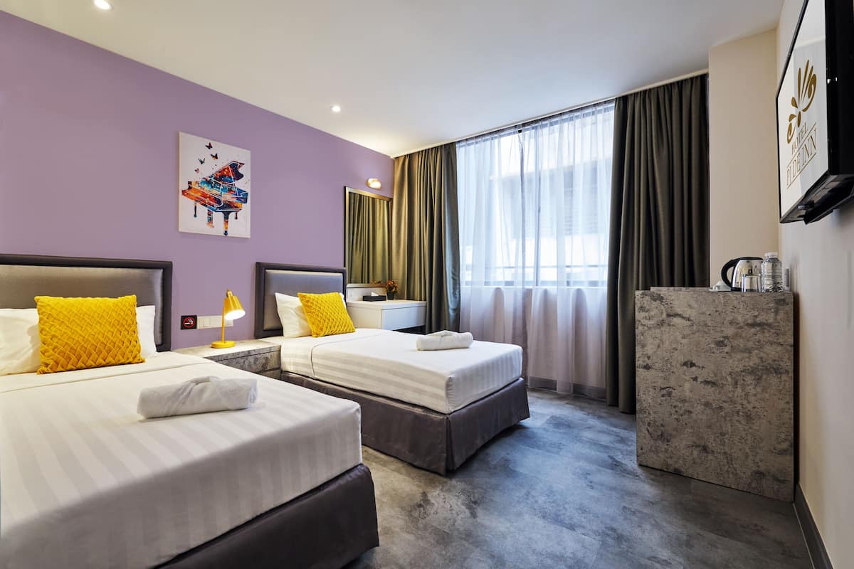 Une chambre d’hôtel avec deux lits, un bureau, un miroir et une télévision.
