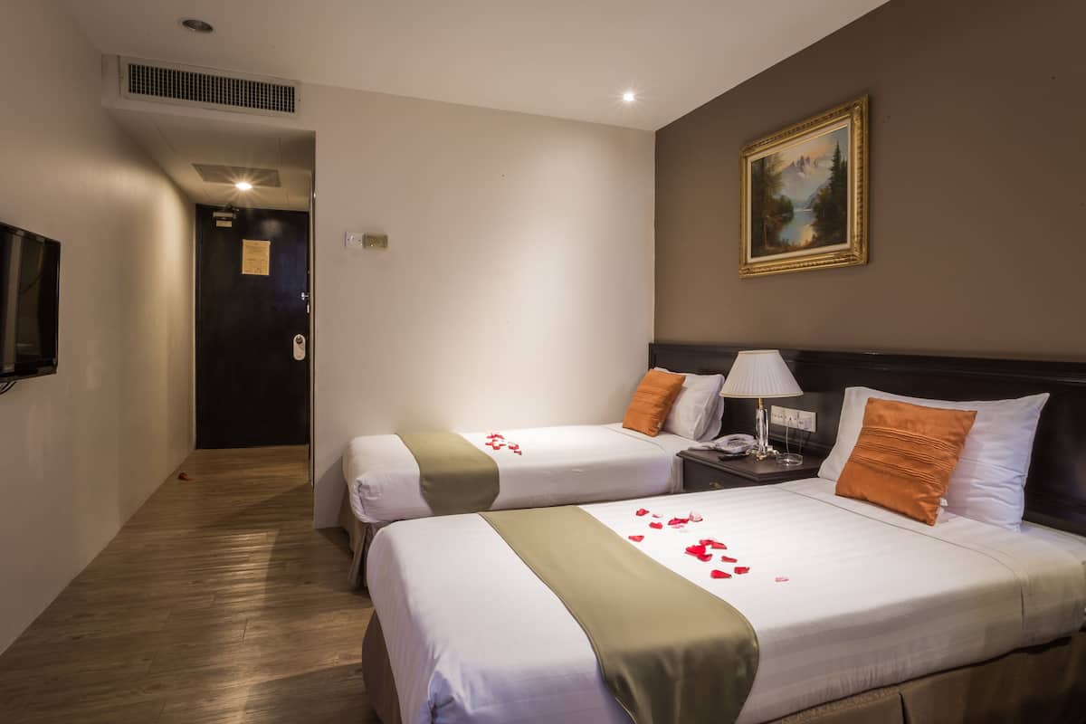 Une chambre d’hôtel avec deux lits, un tableau au mur, une télévision et un plancher en bois.