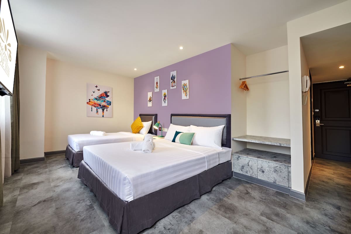 Une chambre d’hôtel avec deux lits, une tête de lit, des œuvres d’art accrochées au mur et une porte de salle de bain.