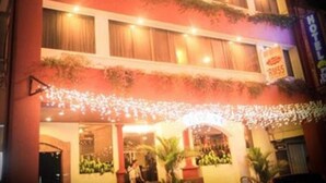Un hotel de varios pisos con fachada curva, ventanas iluminadas y un cartel que indica un precio de RM55 por noche.