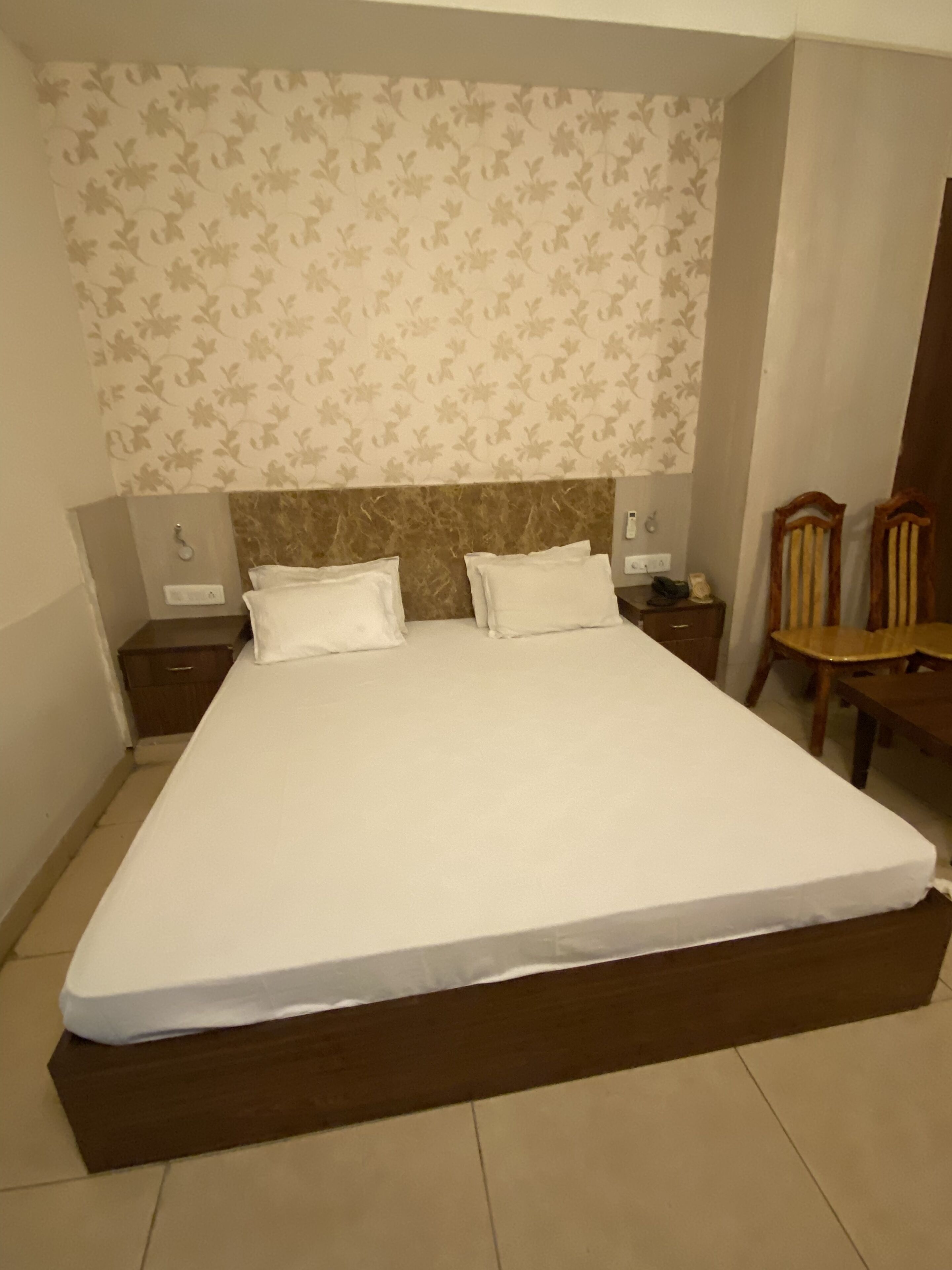 A large bed with a wooden headboard, two bedside tables, and a chair.