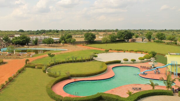Ein großer Pool mit geschwungenem Design, umgeben von gepflegten Rasenflächen und einigen Bäumen.