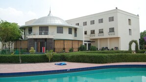 Ein modernes Gebäude mit Schwimmbad, Kuppelbau und einem rechteckigen Gebäude mit Balkonen.