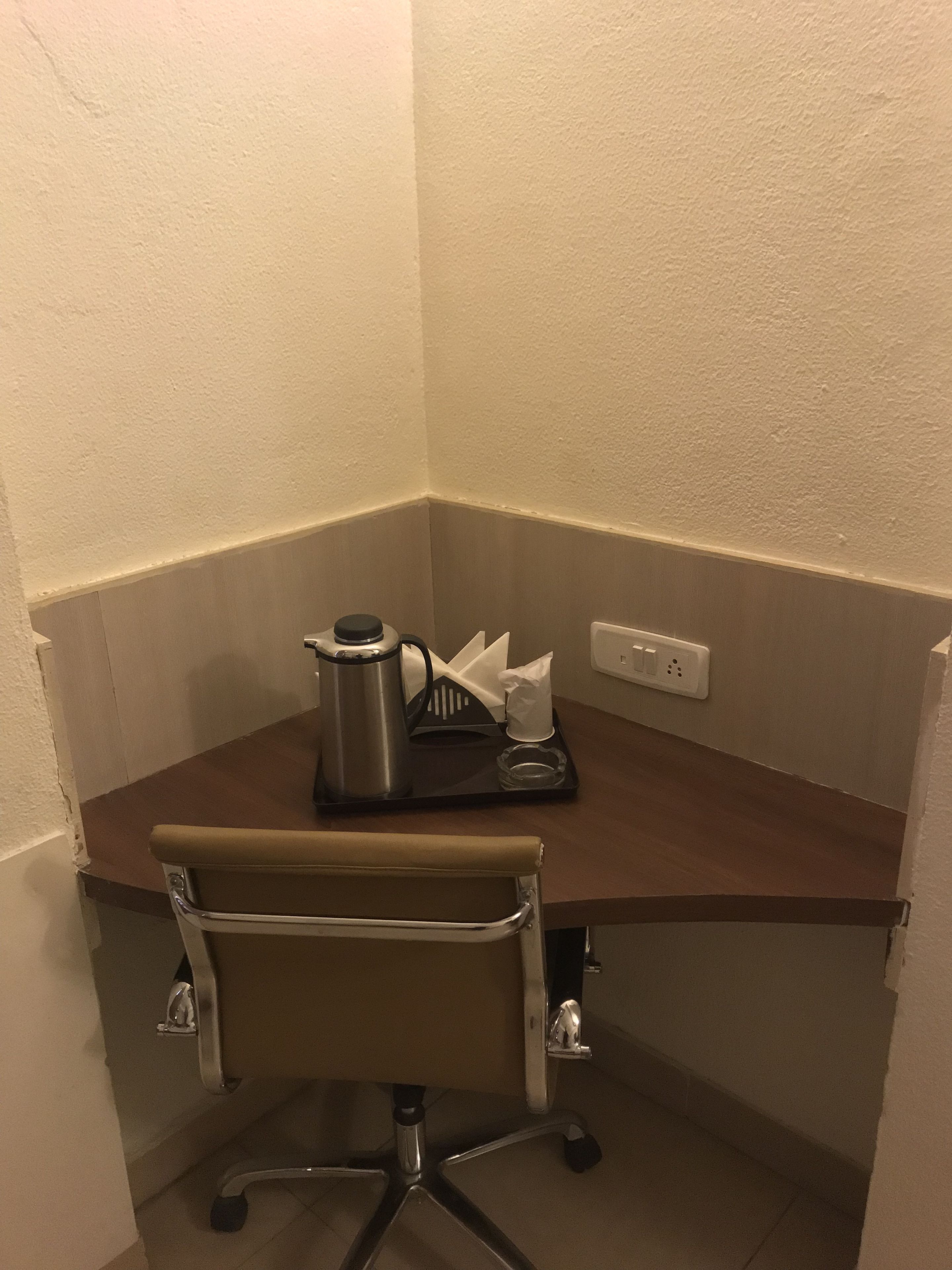 A small office space with a desk, chair, coffee maker, and a tissue box.