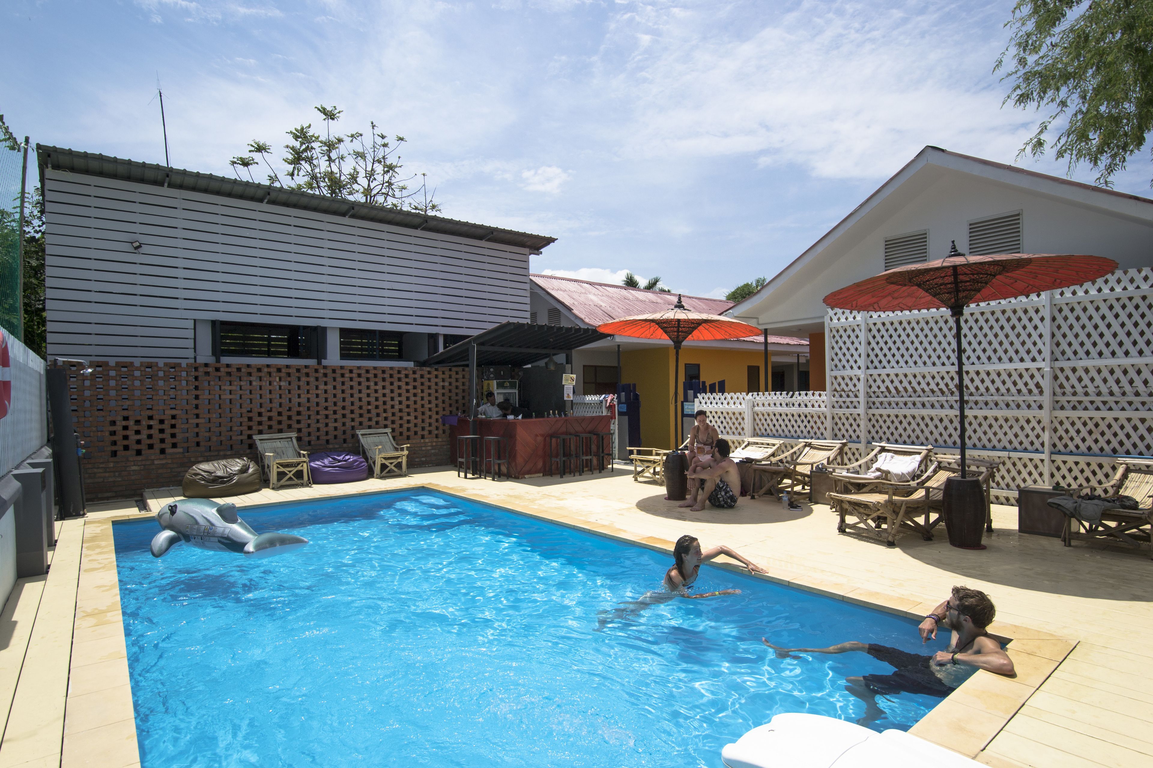 A swimming pool with inflatable toys, lounge chairs, and umbrellas.