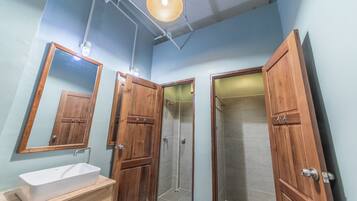 Un baño con tocador de madera, un espejo grande y zona de ducha.