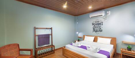 A bedroom with a wooden bed, a wooden chair, a small table, and a wall-mounted air conditioner.