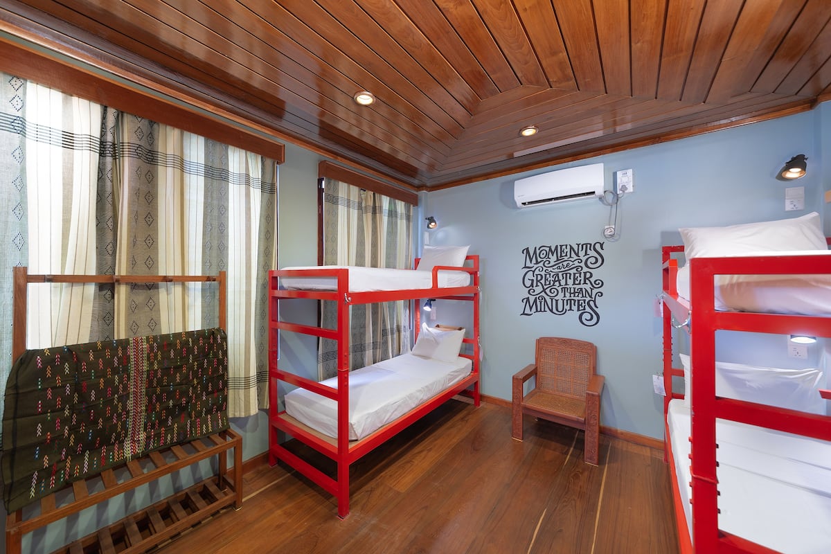 Une chambre avec des lits superposés, une chaise et un mur orné d’une citation inspirante.
