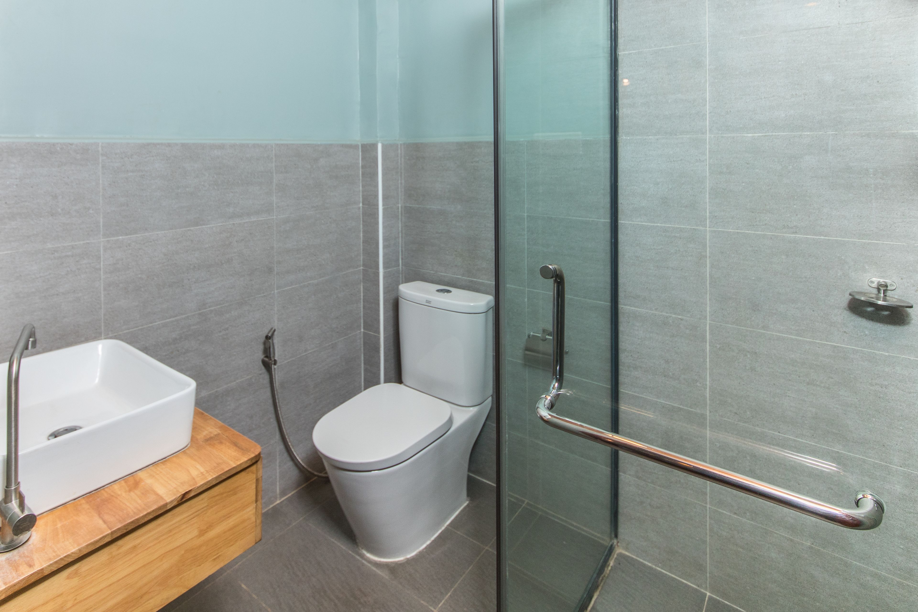 Une salle de bain moderne avec une douche à parois de verre, des toilettes blanches et un meuble-lavabo en bois avec un évier.