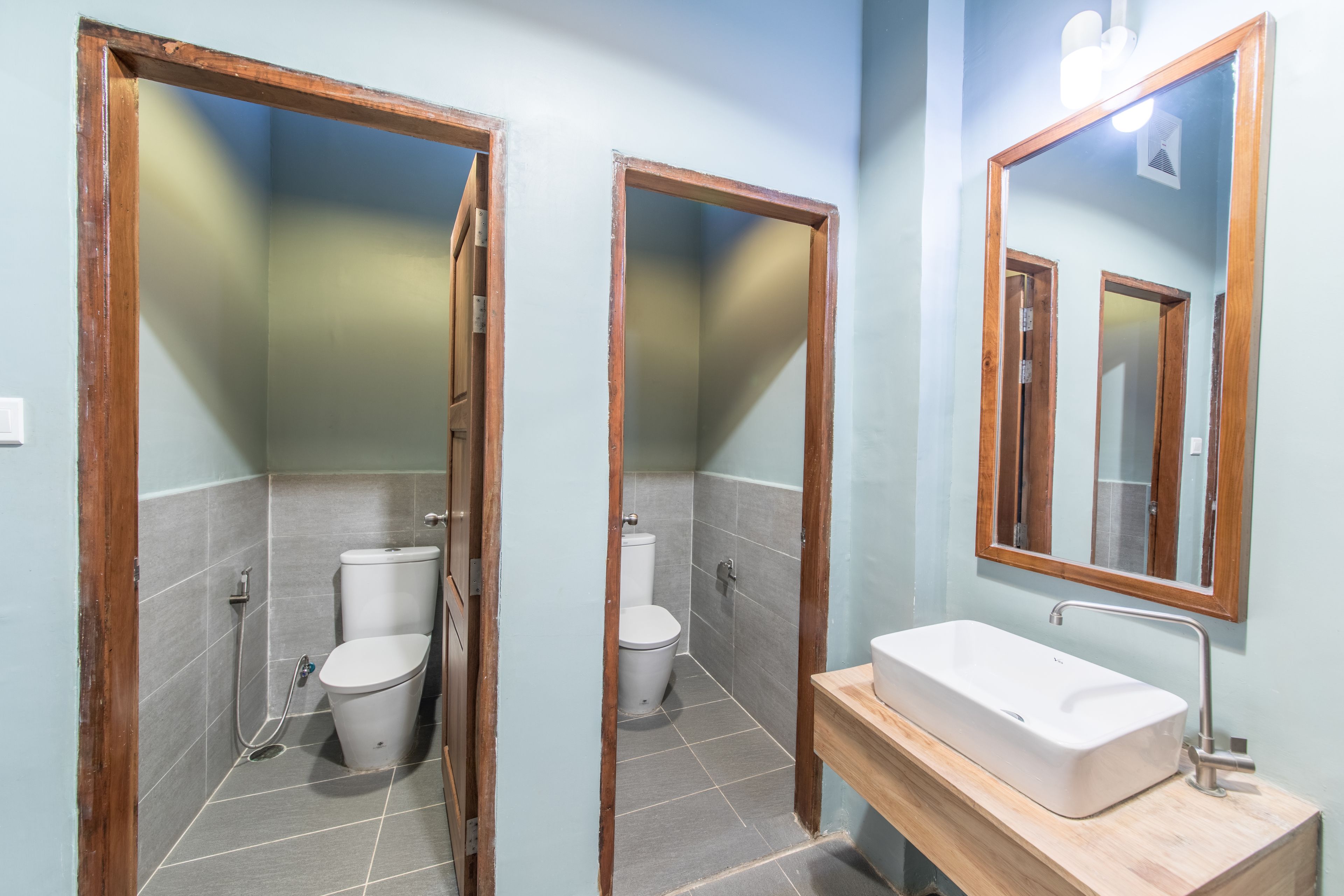 Baño con dos inodoros, un lavabo y un espejo.