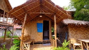 A bamboo hut with a thatched roof, a small porch, and a blue door. - Captain Yut's Bungalow (Koh Lipe)