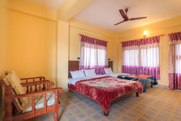 A hotel room with two beds, a wooden chair, a ceiling fan, and patterned curtains. - Hotel Venus (Pokhara)