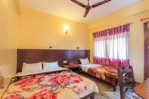 A hotel room with two beds, a wooden headboard, a ceiling fan, a nightstand, a table, and a chair. - Hotel Venus (Pokhara)
