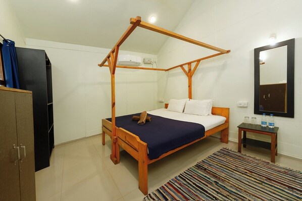 A bedroom with a wooden four-poster bed, a small bedside table, a mirror, and a wardrobe. - Om Shanti Patnem (Canacona)