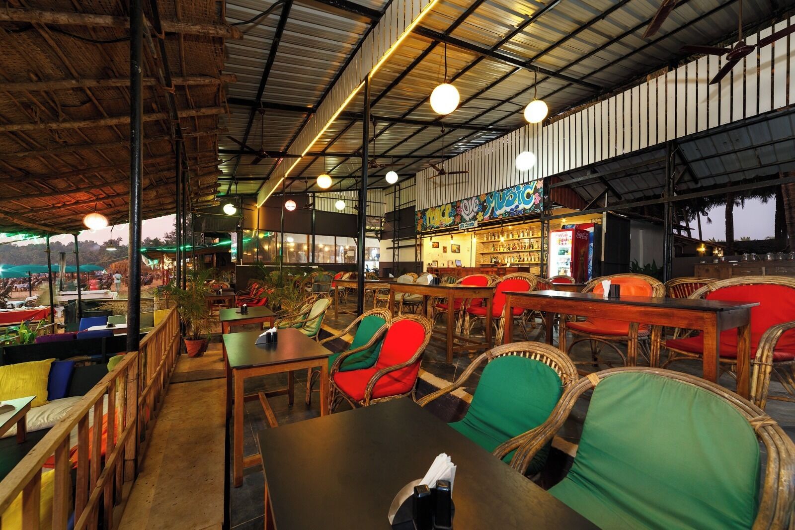 An indoor restaurant with wooden tables and chairs, a bar area, and a view of the outside.