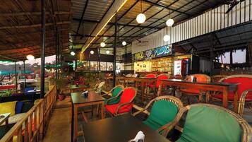 An indoor restaurant with wooden tables and chairs, a bar area, and a view of the outside.