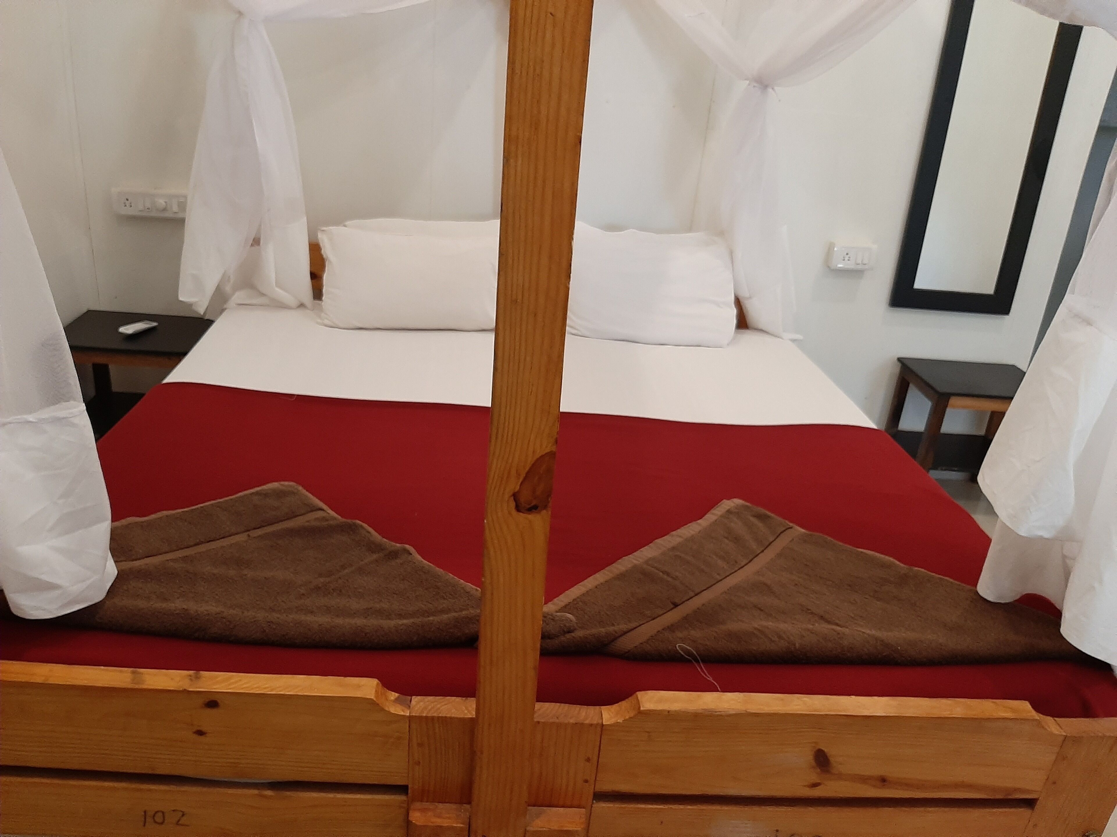 A bed with a red bedspread, white pillows, and a wooden headboard.