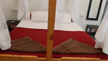 A bed with a red bedspread, white pillows, and a wooden headboard.