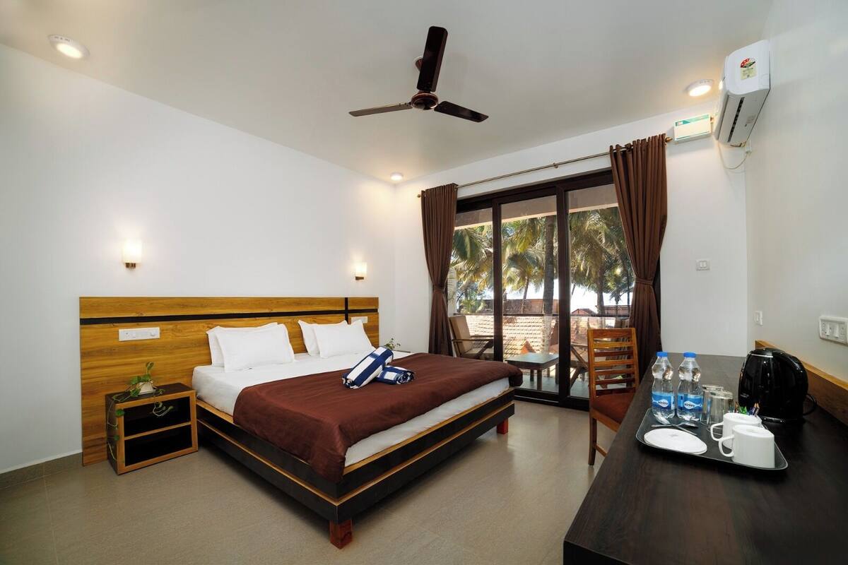 A hotel room with a bed, bedside table, and a desk with a tray of breakfast items.