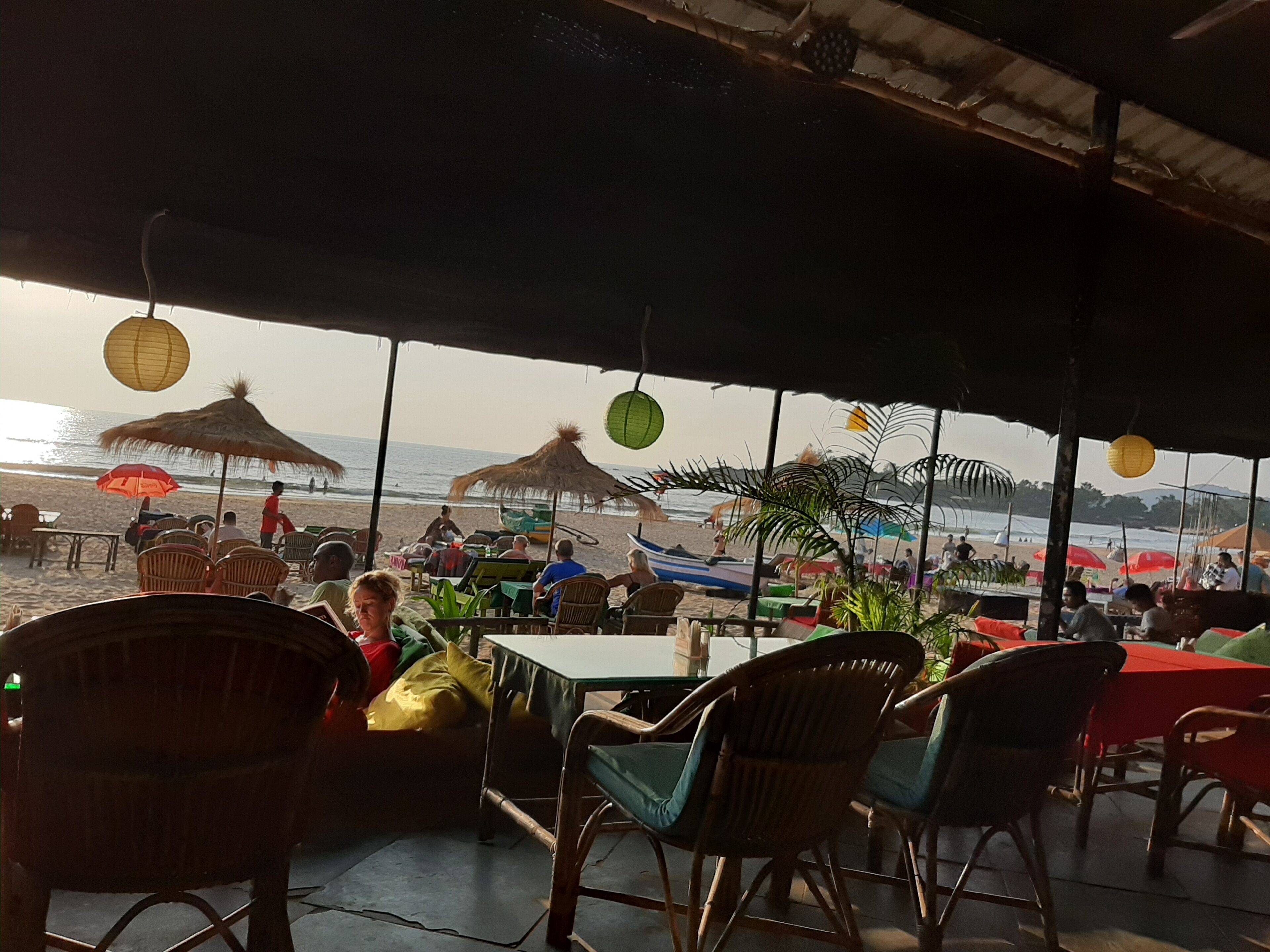An outdoor seating area with tables and chairs, overlooking a beach.