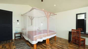 Une pièce avec un plancher en bois, un lit à baldaquin, un bureau avec une chaise, un miroir et une porte.