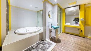 A modern bathroom with a large bathtub, a sink with a blue basin, and a mirror above the sink. - In Hotel (Suwon)