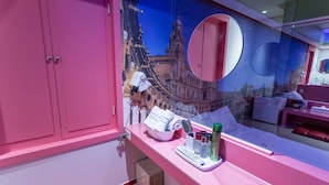 A bathroom with a pink vanity, a mirror, and a decorative wall mural. - In Hotel (Suwon)