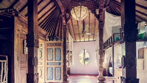 A spacious hallway with wooden architecture, a chandelier, and a large mirror. - Dragonfly Village (Ubud)