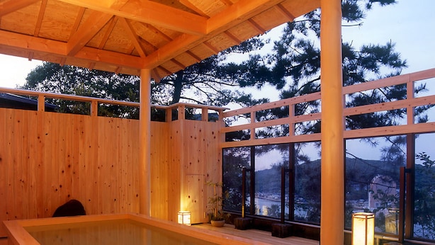 A wooden spa with a hot tub, large windows, and a view of trees and hills. - Ama no shima (Toba)