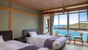 A hotel room with two beds, a small table, and a view of the sea. - Ama no shima (Toba)