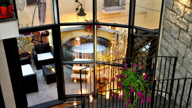 A view from a balcony overlooking a cozy courtyard with a hot tub, seating area, and potted plants. - Hotel Antica Posada (Loceri)