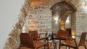 A stone-walled dining area with wooden chairs and a table set for a meal. - Hotel Antica Posada (Loceri)