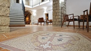 A spacious lobby with a tiled floor, stone pillars, and a staircase leading to an upper level. - Hotel Antica Posada (Loceri)