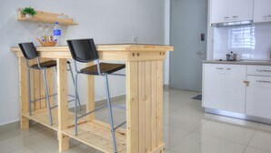 A kitchen with a wooden bar stool area, white cabinets, and a door. - Cybersquare B2210 (Cyberjaya)