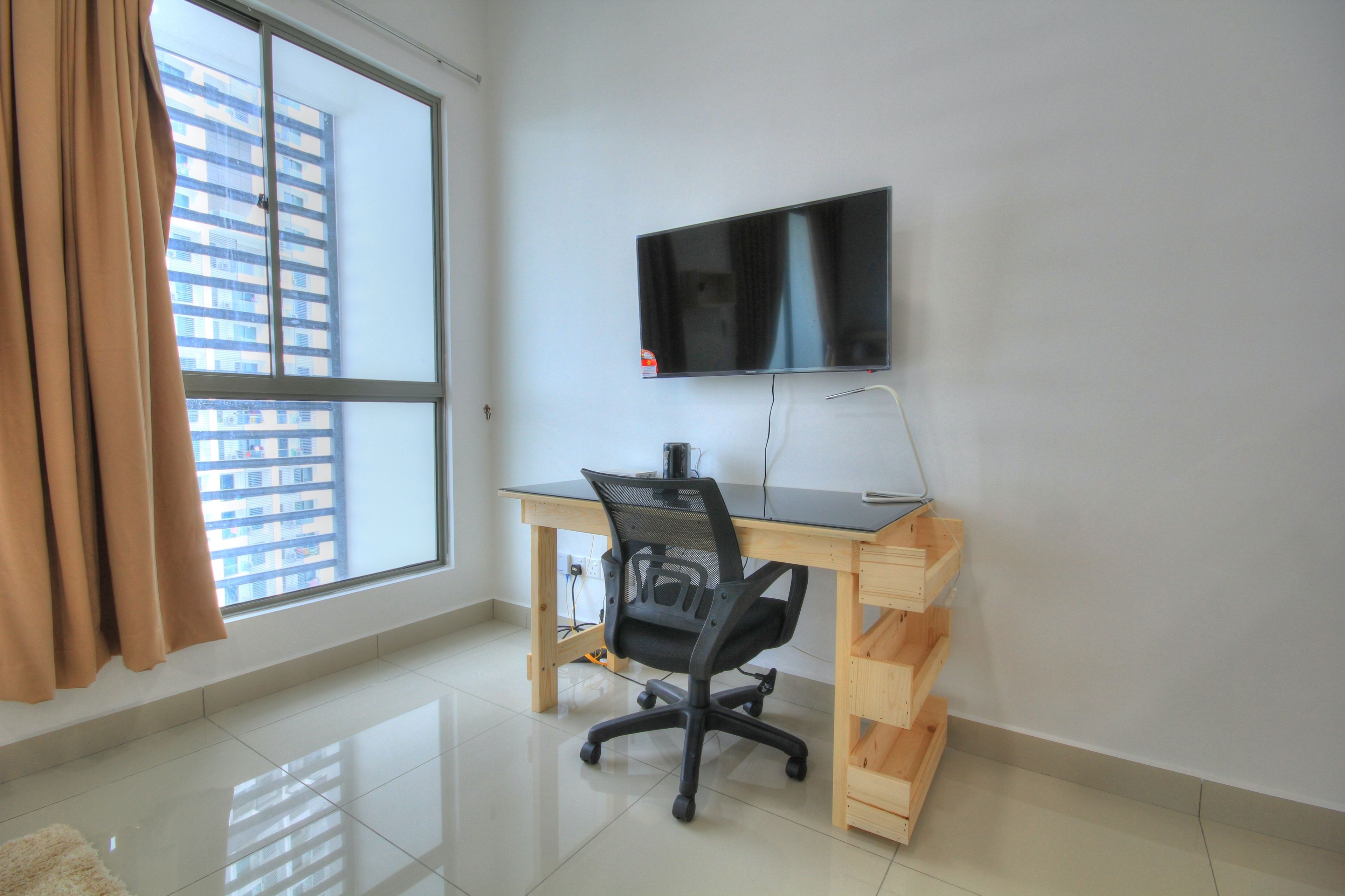 A modern office space with a large window, a desk, a chair, and a mounted TV.