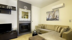 A modern living room with a flat-screen TV, a fireplace, a sofa, and decorative wall art. - Antigone Estate (Rhodes)