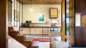A modern kitchen with wooden cabinets, a built-in stove, and a hanging light fixture.