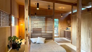 A modern bedroom with a bed, wooden slats, and a view of the outdoors.