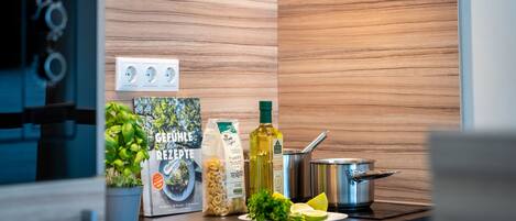 A kitchen with a wooden backsplash, a stove, a sink, and various food items on the counter.