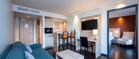 Een moderne woonkamer met een bank, een salontafel en een werkhoek met stoelen.