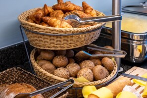 Un buffet avec des paniers de pain, de croissants et de petits pains.